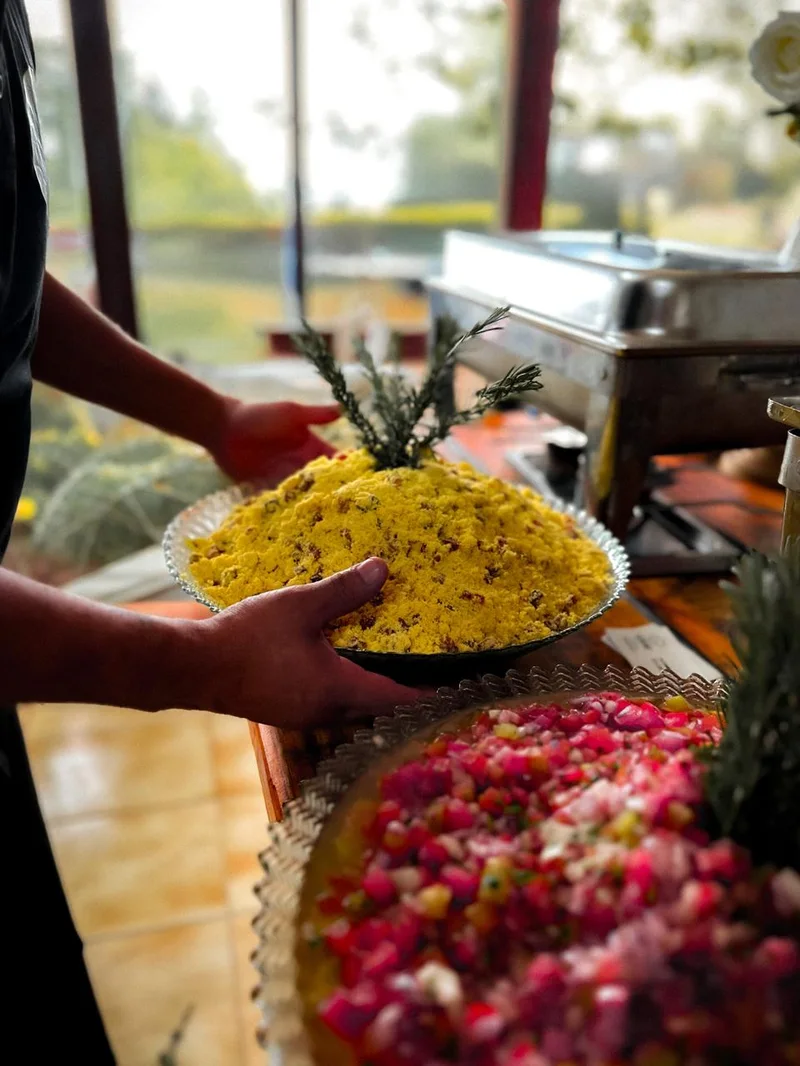 Chef finalizando estação gastronômica com vinagrete e acompanhamentos frescos